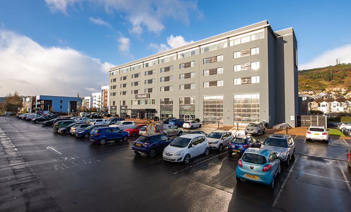 Exterior shot of a hotel and its car park.